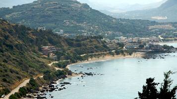 A coastal town with a winding road, rocky shoreline, and buildings on a hillside.