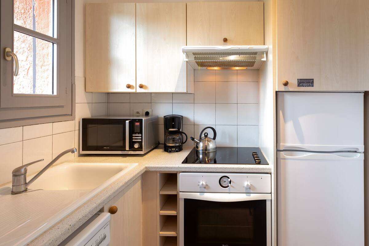 Una cocina moderna con microondas, cafetera, hervidor, estufa, horno y refrigerador.