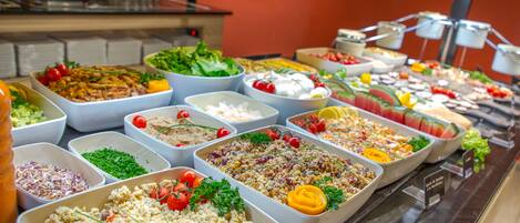 A buffet with various dishes including salads, fruits, and other food items.