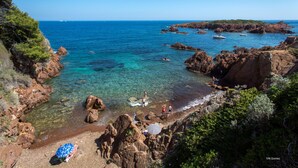 A coastal beach with rocky terrain, clear water, and people enjoying the area. - SOWELL RÉSIDENCES Les Chênes Verts (Saint-Raphael)