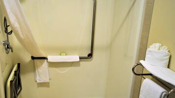 A bathroom with a shower, grab bars, and a towel rack.