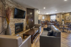 Een ruime zithoek met een open haard, zachte zitplaatsen, een flatscreen-tv en een eethoek met tafels en stoelen.