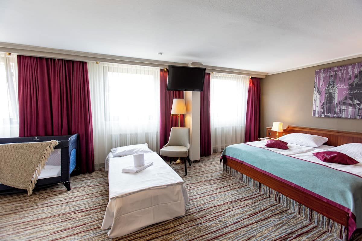 Ein Hotelzimmer mit Bett, Stuhl, Schreibtisch und Fernseher.