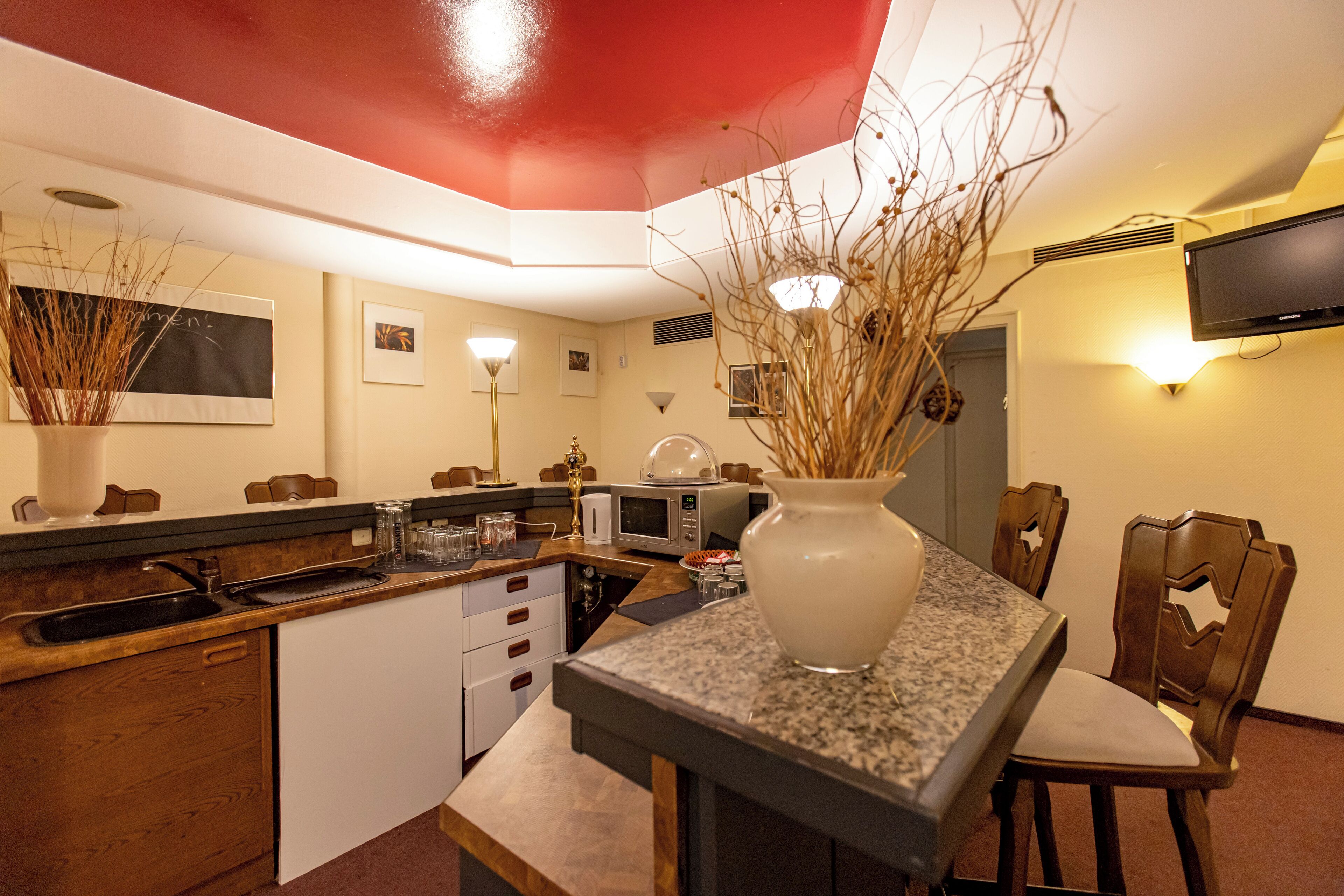 A modern kitchen with a red ceiling, a built-in oven, a microwave, and a sink.