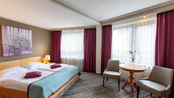 Habitación de hotel con una cama, dos sillas, una mesita y un cuadro en la pared.