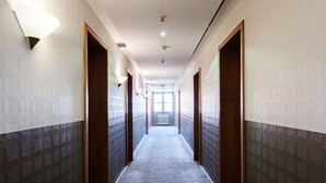 A long, narrow hotel corridor with carpeted floors and wooden doors on both sides.
