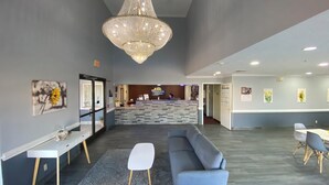 A reception area with a chandelier, a reception desk, a sofa, and a coffee table. - Days Inn & Suites by Wyndham Winnie (Winnie)