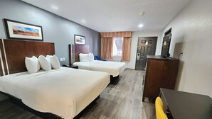 A hotel room with two beds, a desk, a chair, a television, and a window with curtains. - Days Inn & Suites by Wyndham Winnie (Winnie)
