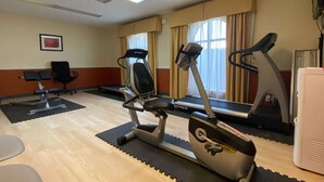 A gym with exercise equipment, a treadmill, an elliptical, and a stationary bike. - Days Inn & Suites by Wyndham Winnie (Winnie)