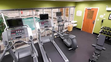 A gym with treadmills, an elliptical, and dumbbells.