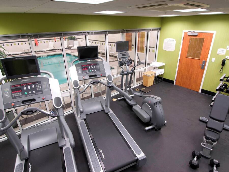 A gym with treadmills, an elliptical, and dumbbells.