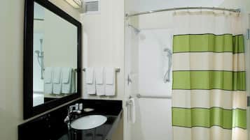 A bathroom with a black sink, white tiles, a large mirror, and a shower curtain with green and beige stripes.