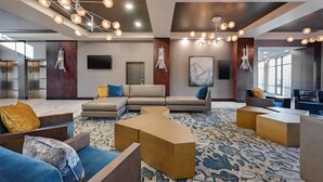 A modern lobby with sofas, a coffee table, and artwork on the walls. - DoubleTree by Hilton Denver International Airport (Denver)