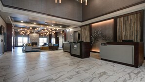 A spacious lobby with a reception desk, seating area, and a fireplace. - DoubleTree by Hilton Denver International Airport (Denver)