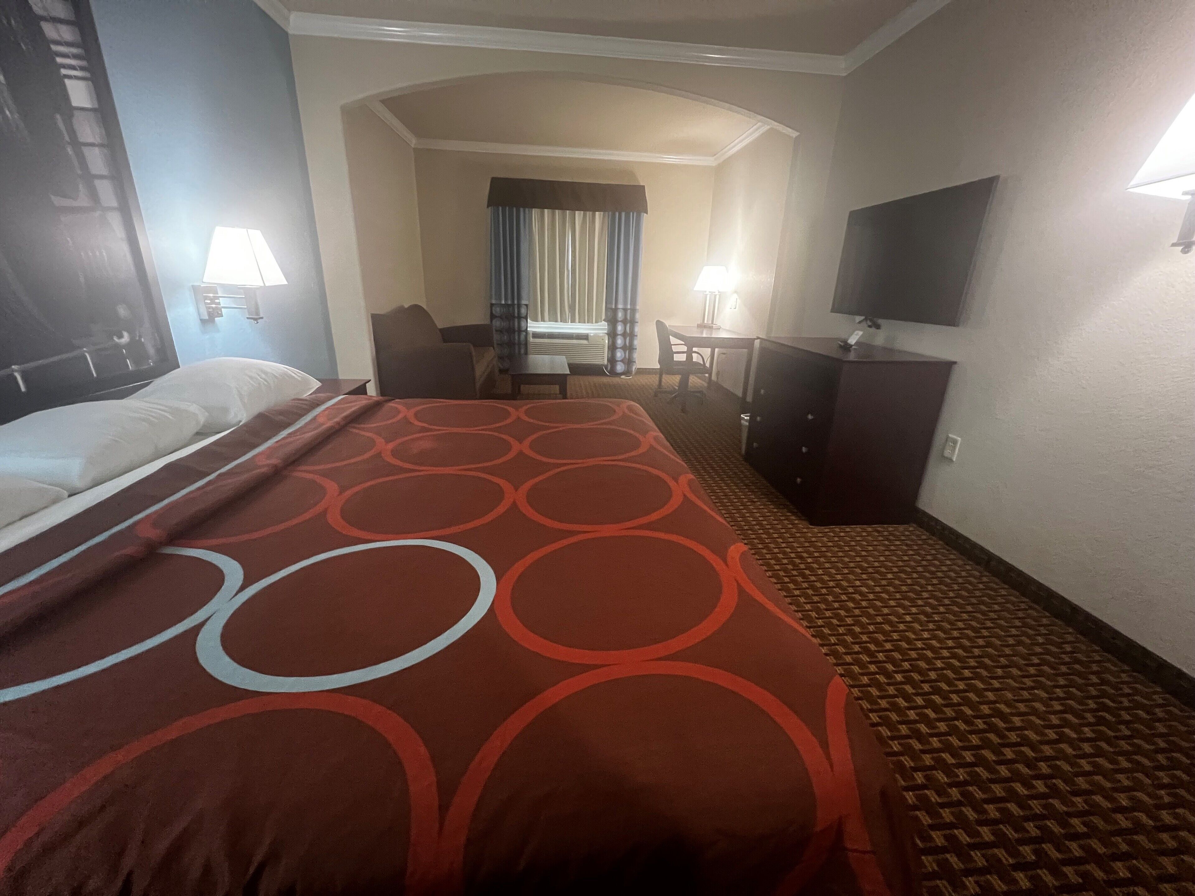 A hotel room with a bed, a desk, a chair, a television, and a wardrobe.