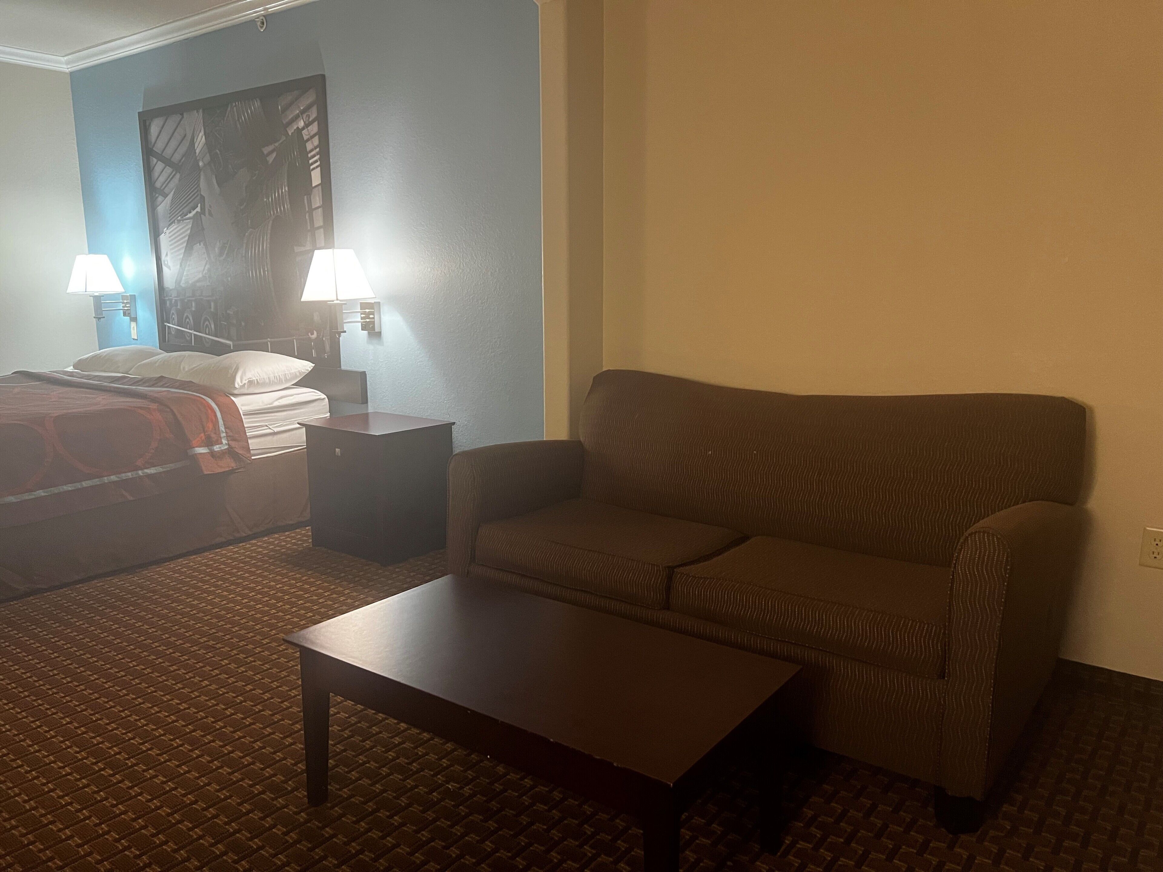 Une chambre d’hôtel avec un lit, un canapé, une petite table et une lampe.