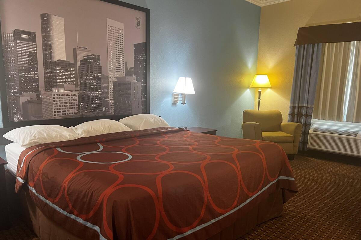 Une chambre d’hôtel avec un lit, une vue sur la ville, une lampe et une chaise.