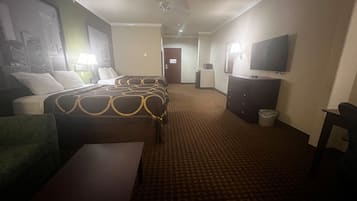 Habitación de hotel con dos camas, un escritorio, una silla, un televisor, una lámpara y un cesto de basura.
