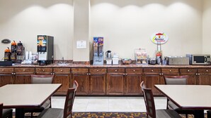 Een ontbijtruimte in een hotel met houten kasten, een koffieapparaat, een magnetron en een bordje met de tekst 'Sopasart breakfast'.