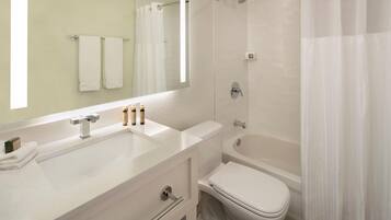A modern bathroom with a white sink, mirror, and toilet. There are two towels hanging on the wall, and a shower curtain is partially visible.