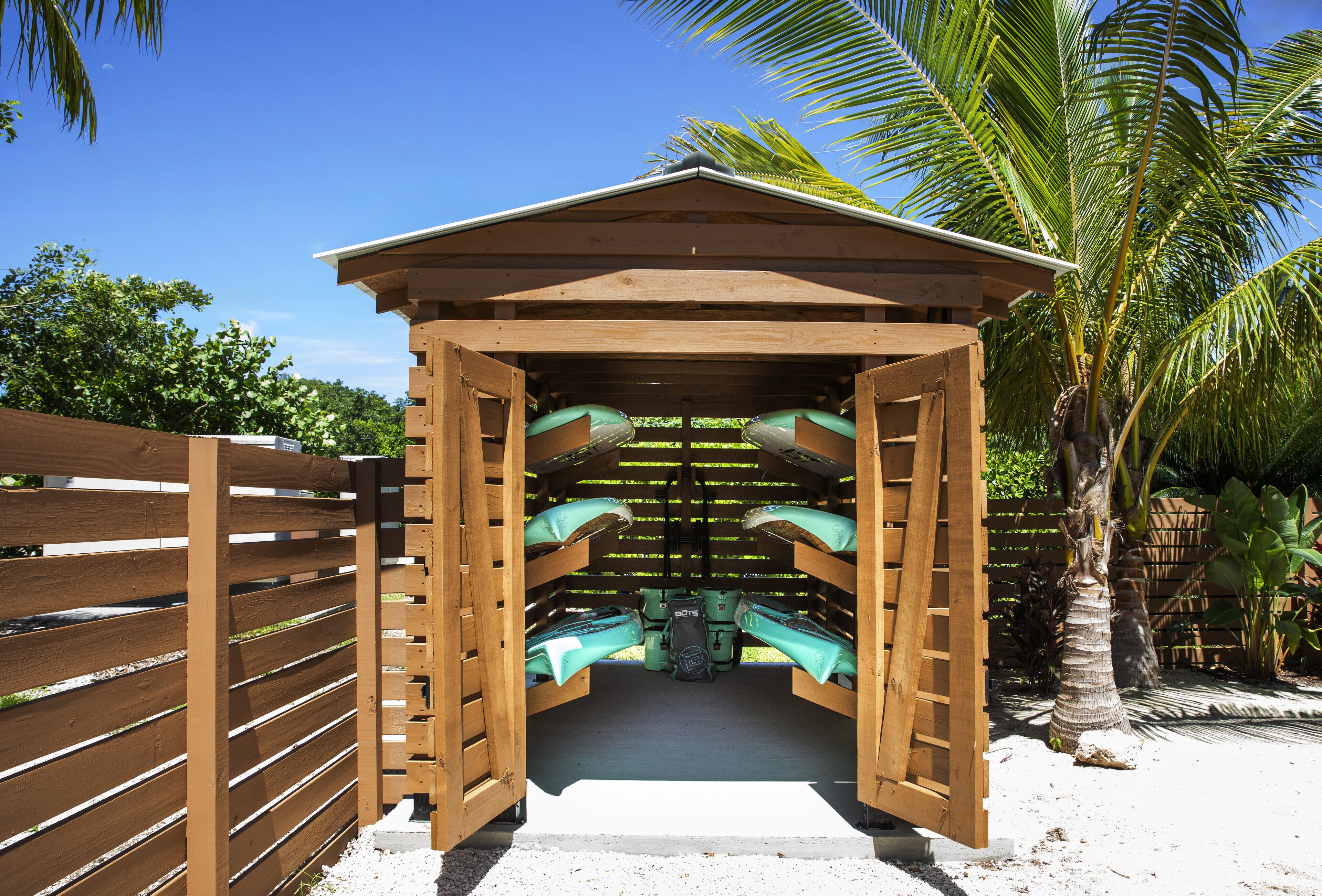 A wooden structure with a roof, possibly a gazebo or shelter, with two green kayaks inside.