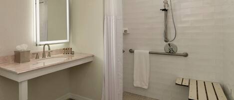 A modern bathroom with a sink, mirror, shower, and a wooden floor.