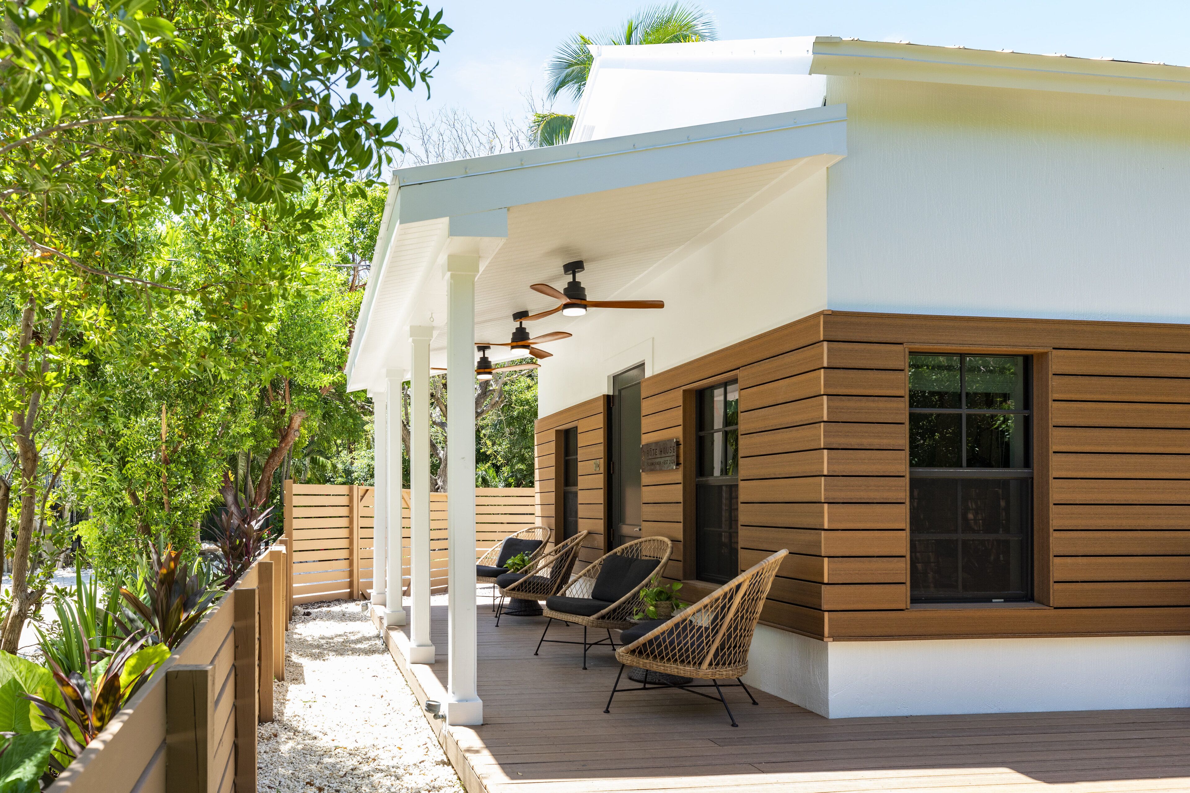 A modern house with a covered porch, wooden deck, and outdoor seating area.