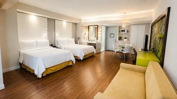 A hotel room with two beds, a sitting area, a dining table, and a kitchenette.