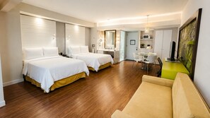 Een hotelkamer met twee bedden, een zithoek, een eettafel en een kitchenette.
