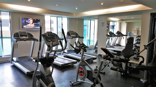 Een fitnessruimte met loopbanden, elliptische trainers en gewichten.