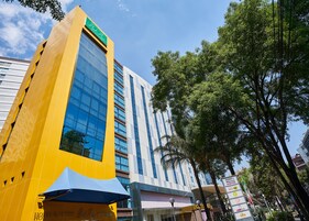 Un hôtel moderne avec une façade jaune et une enseigne verte.