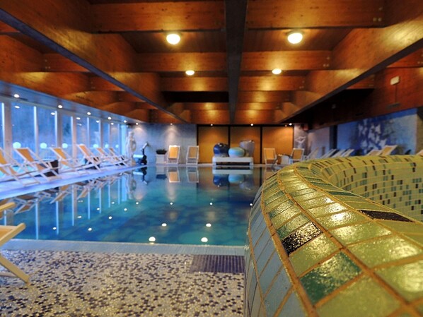 Una piscina con sillas de descanso y una pared de mosaicos.