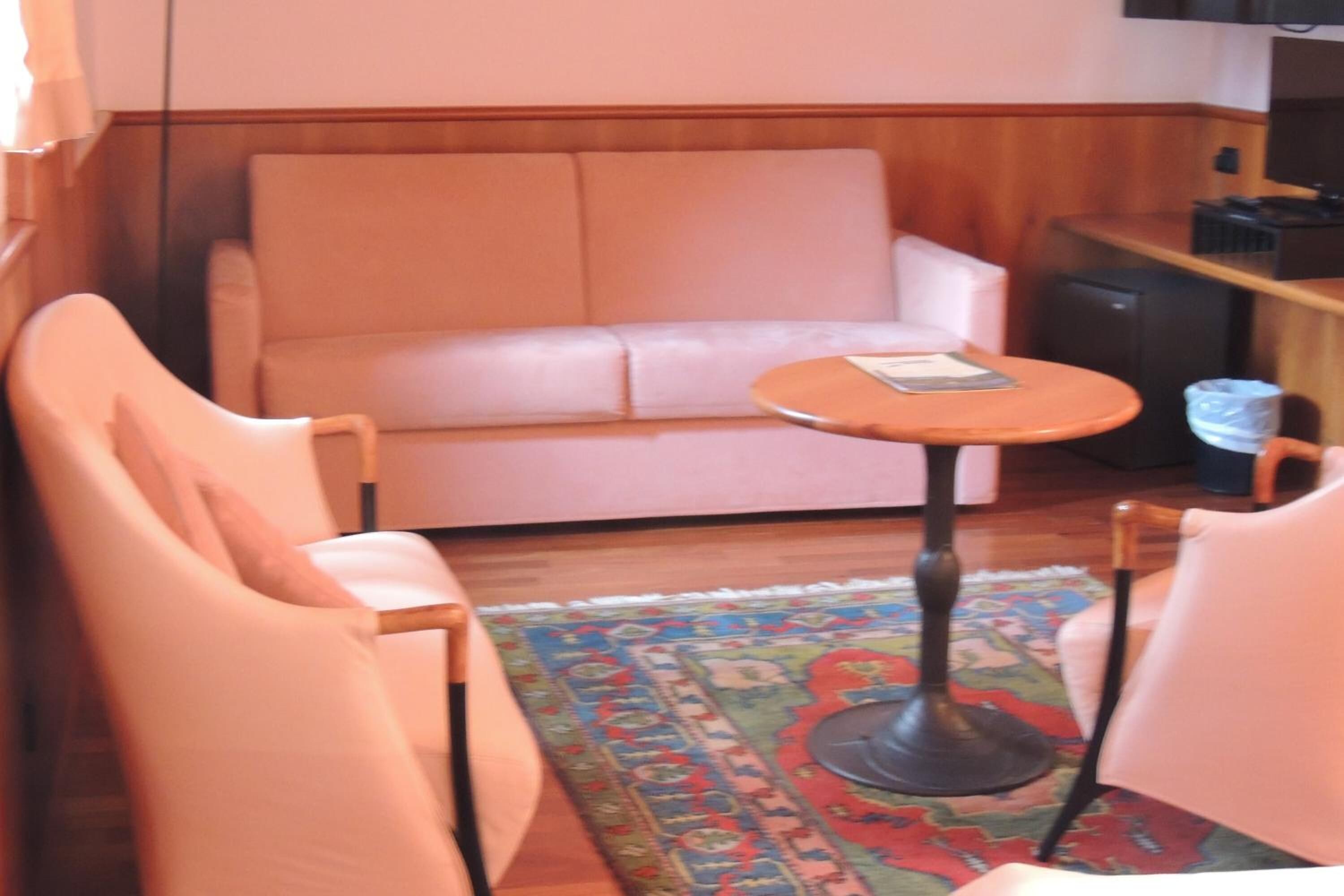 A room with a white sofa, a small round table, and a patterned rug.