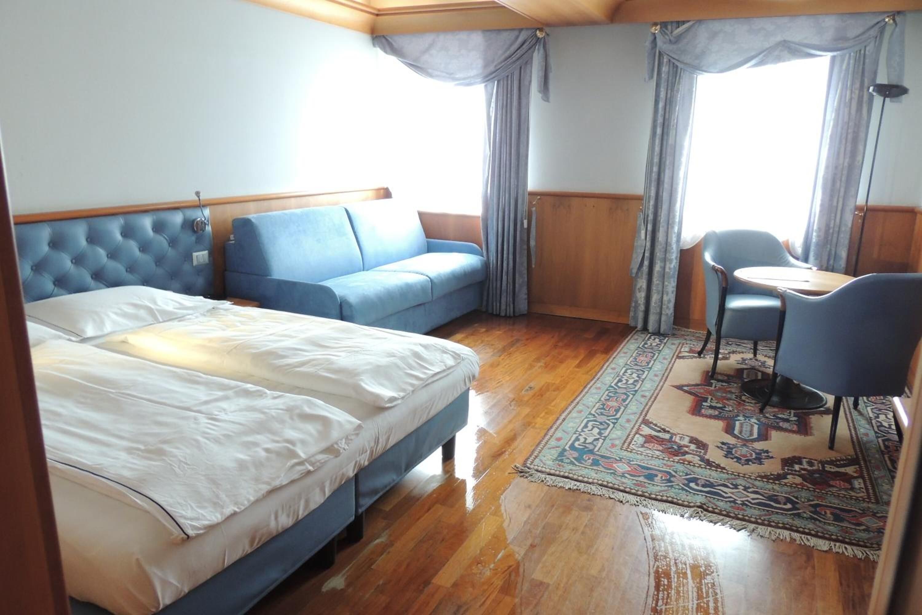 Una habitación con una cama, un sofá azul, una mesita y una silla.
