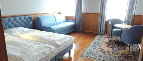 Una habitación con una cama, un sofá azul, una mesita y una silla.