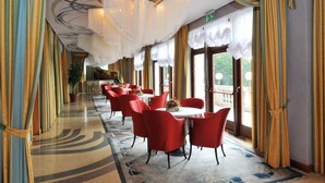 A dining area with red chairs, white tables, and a patterned carpet. - Grand Hotel Astoria (Lavarone)