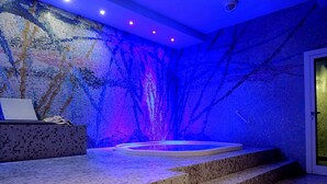 A spa area with a mosaic wall, a hot tub, and a reception desk. - Grand Hotel Astoria (Lavarone)