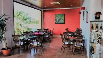 A conference room with a large screen, wooden tables, wicker chairs, and a wine display.