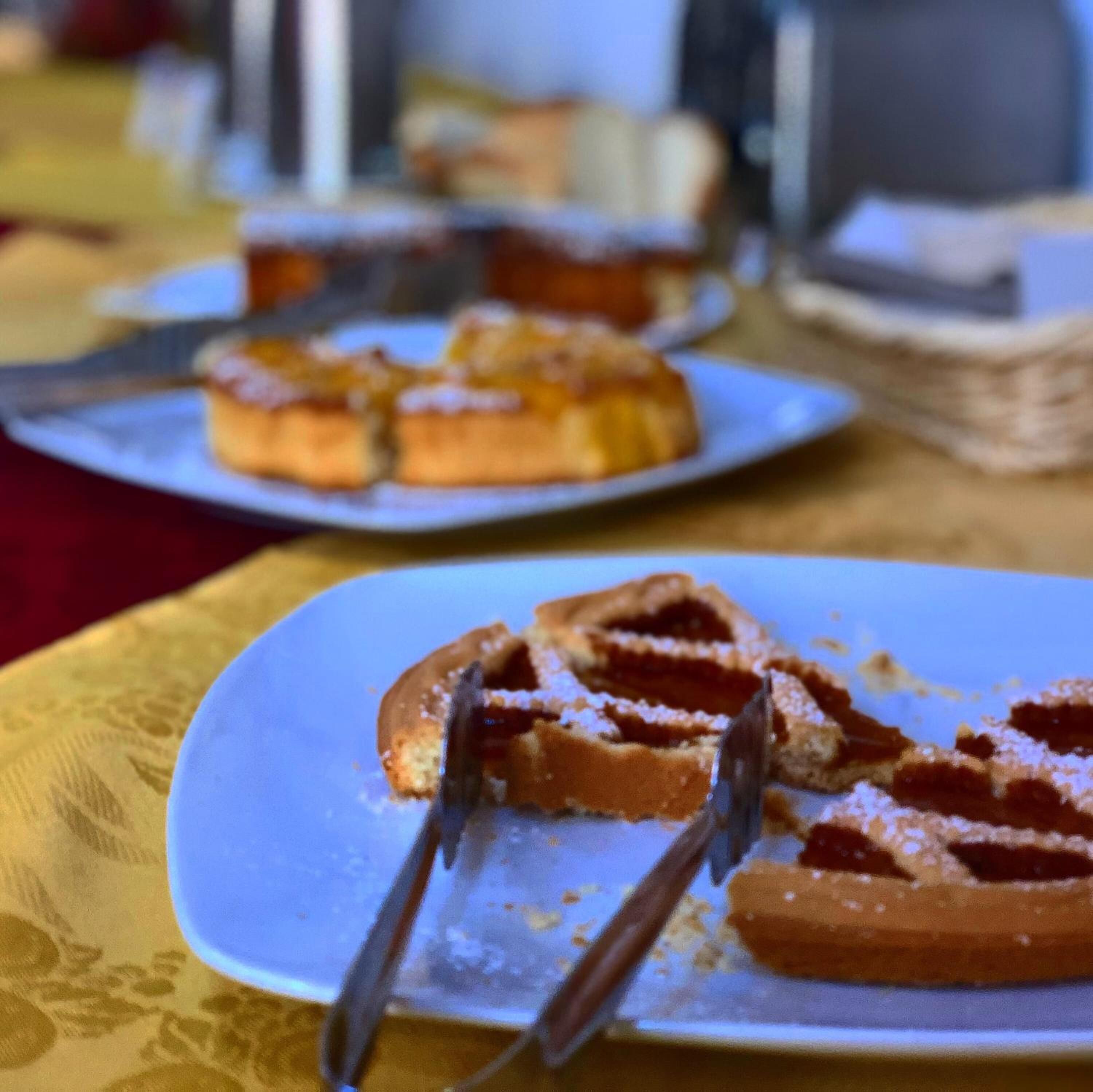 A plate with a dessert, possibly a tart or pie, on a table with a patterned tablecloth.