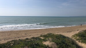 Una playa con cielo despejado y mar tranquilo.