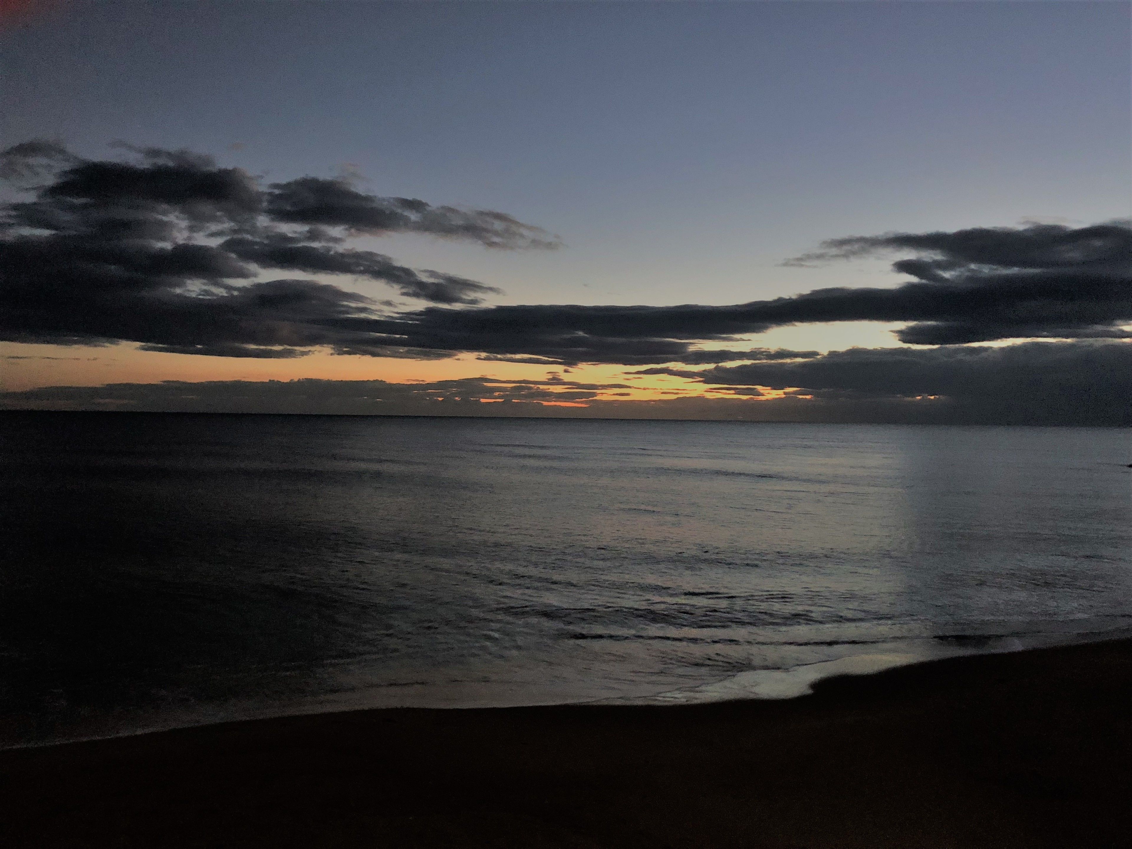 Una spiaggia con mare calmo e un tramonto.