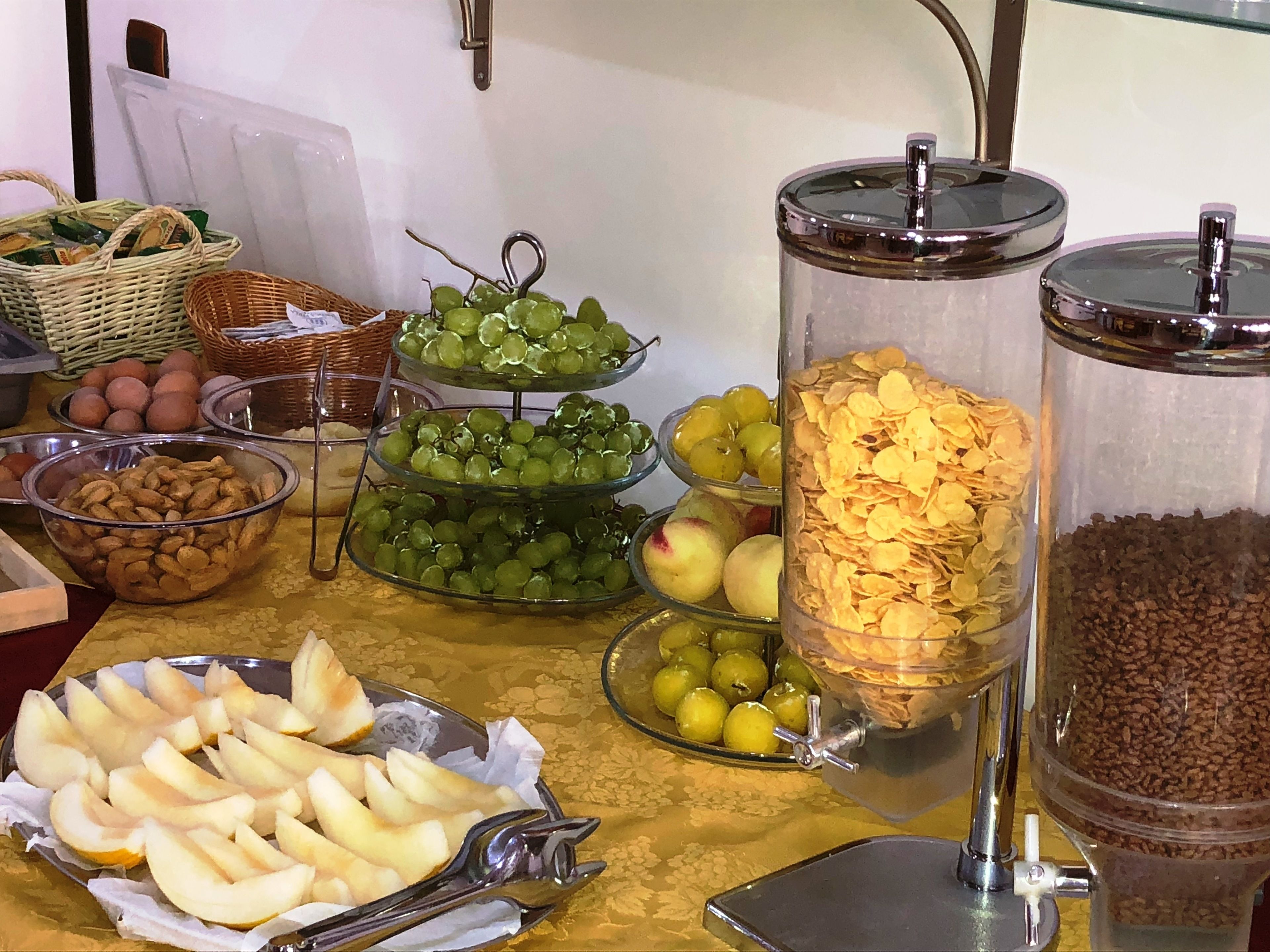 Una mesa de buffet con diversas opciones de comida, incluyendo uvas, manzanas y cereales.