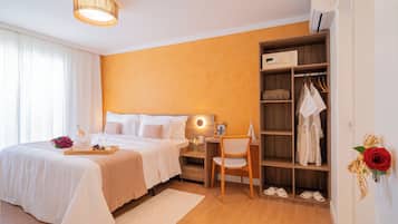 A hotel room with a bed, bedside table, desk, chair, wardrobe, and a red rose decoration.