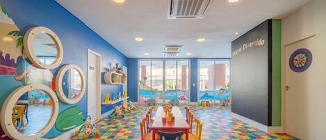 A vibrant children's playroom with colorful checkered flooring, a long table, and playful wall decorations.