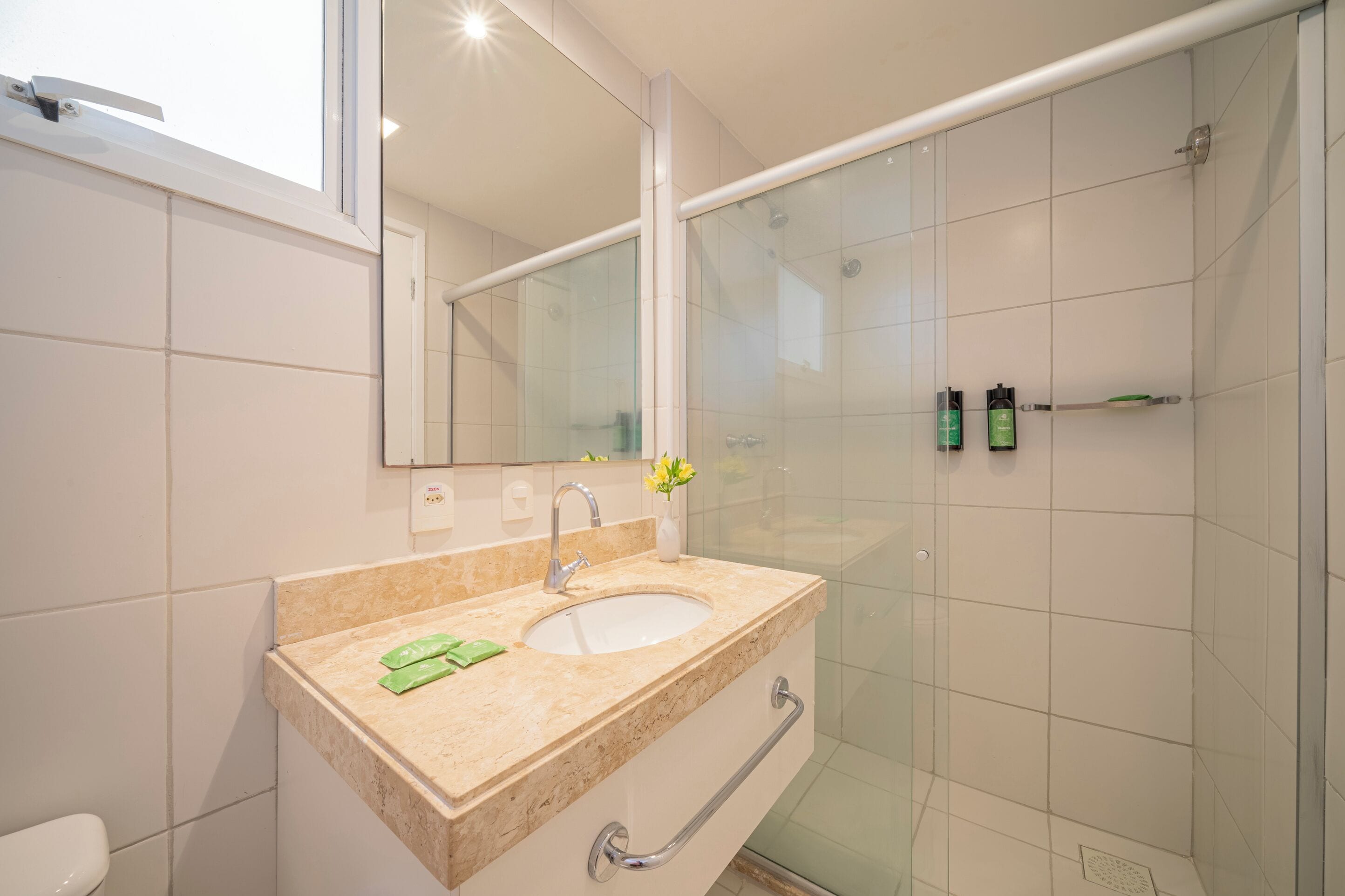Un baño moderno con lavamanos, espejo y cabina de ducha de vidrio.