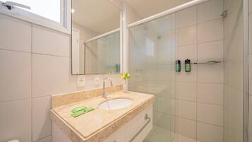 Un baño moderno con lavamanos, espejo y cabina de ducha de vidrio.