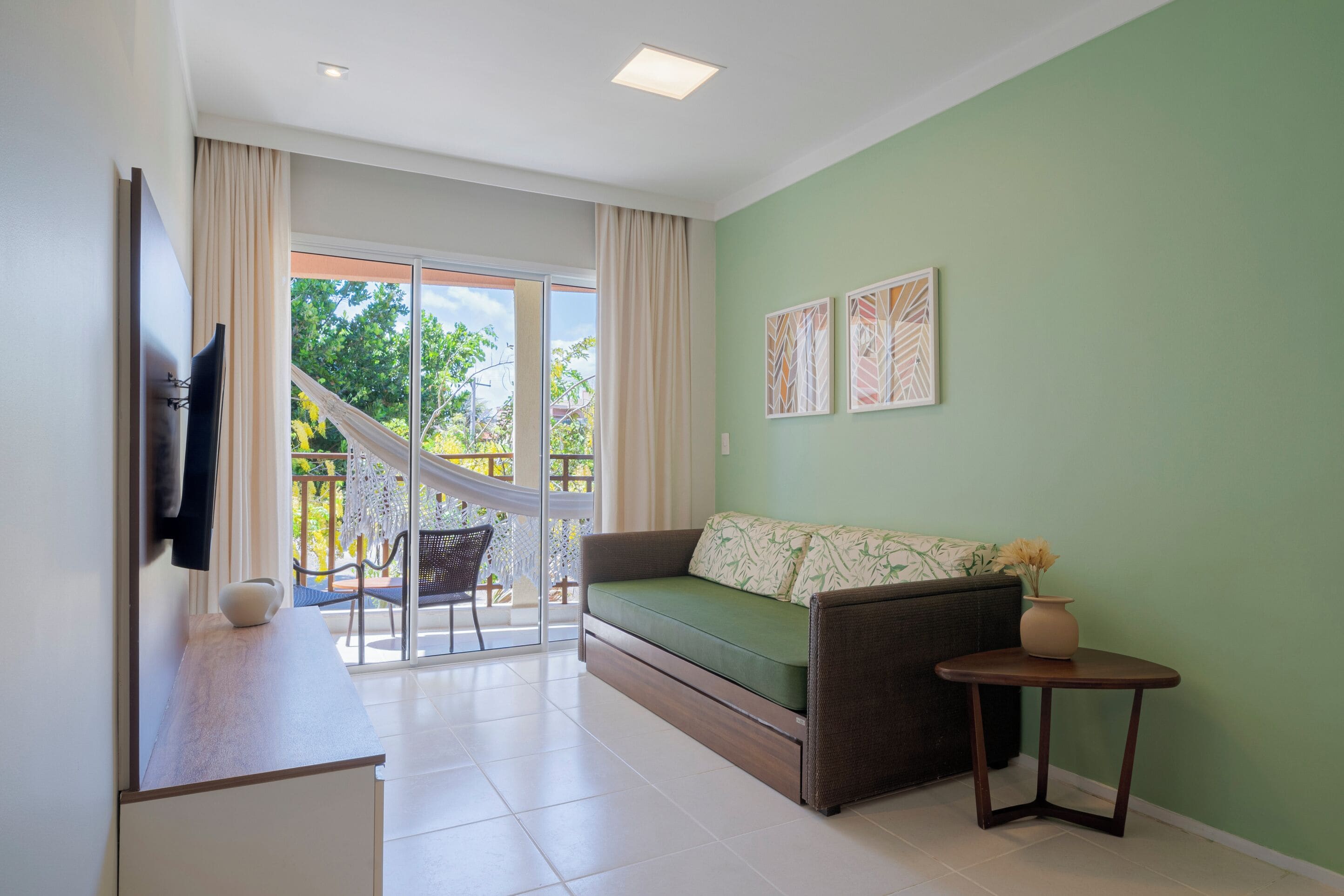 A living room with a sofa, a small table, and a TV mounted on the wall.