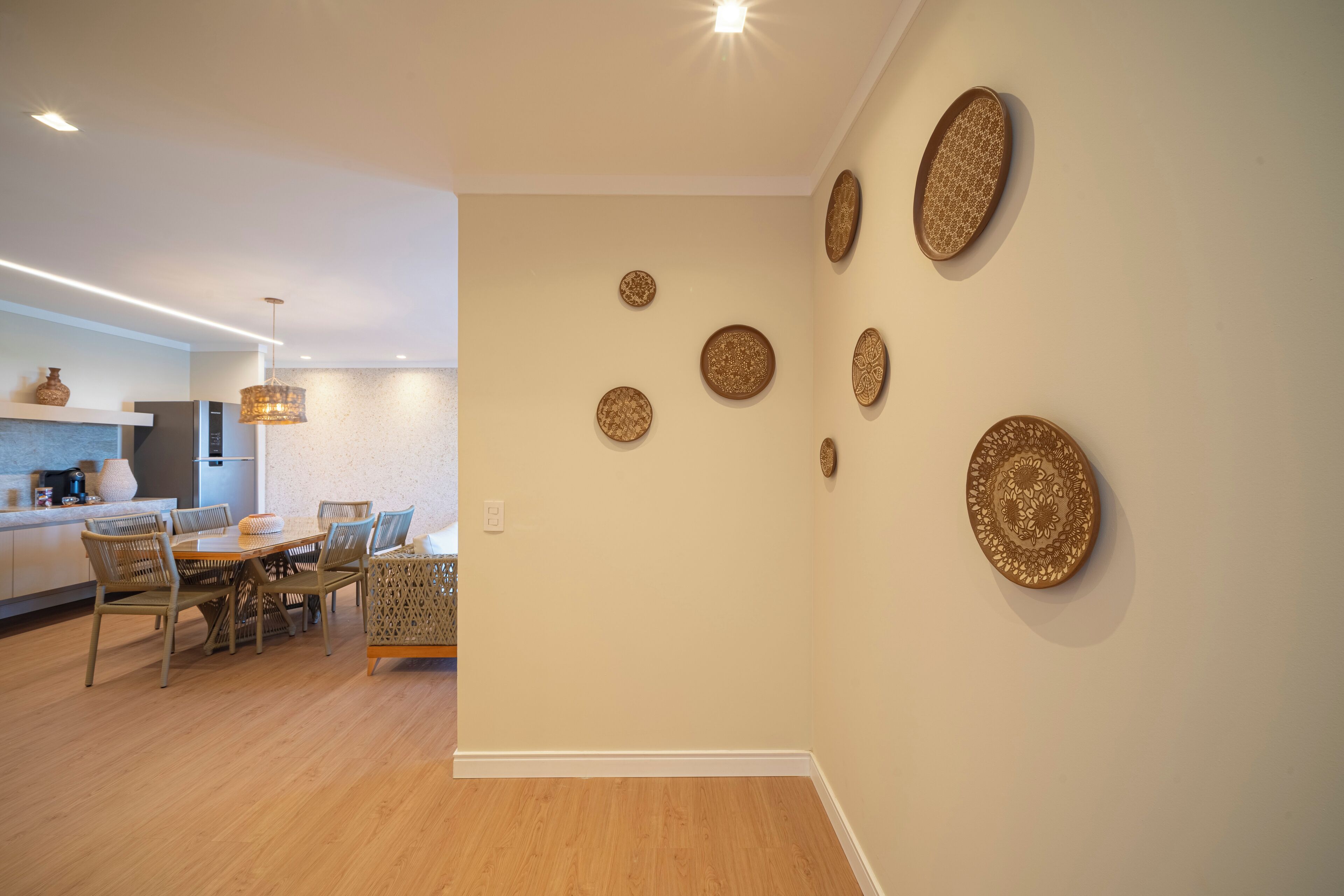 Una cocina moderna con comedor, que incluye una mesa y sillas de madera, una lámpara colgante y placas decorativas en la pared.