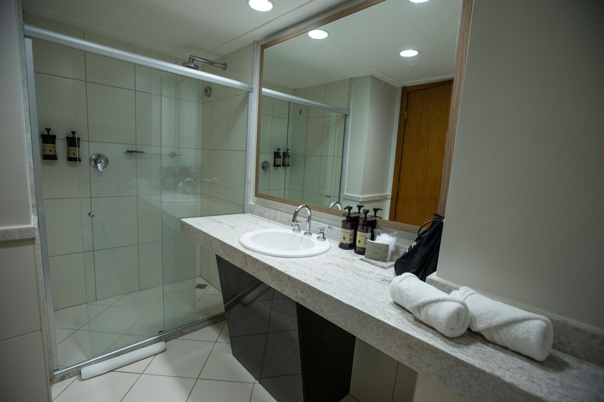 A modern bathroom with a glass-enclosed shower, a marble sink, and a large mirror.