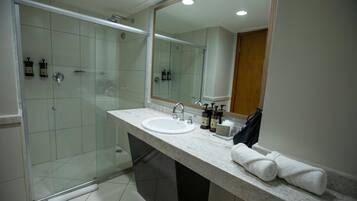 A modern bathroom with a glass-enclosed shower, a marble sink, and a large mirror.